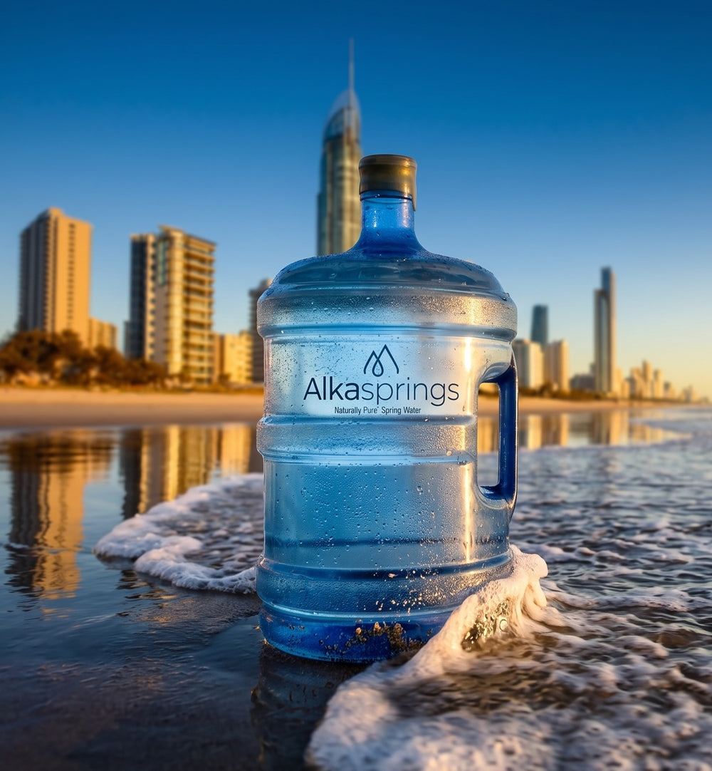 Alkasprings spring water bottle on a beach with the Gold Coast skyline