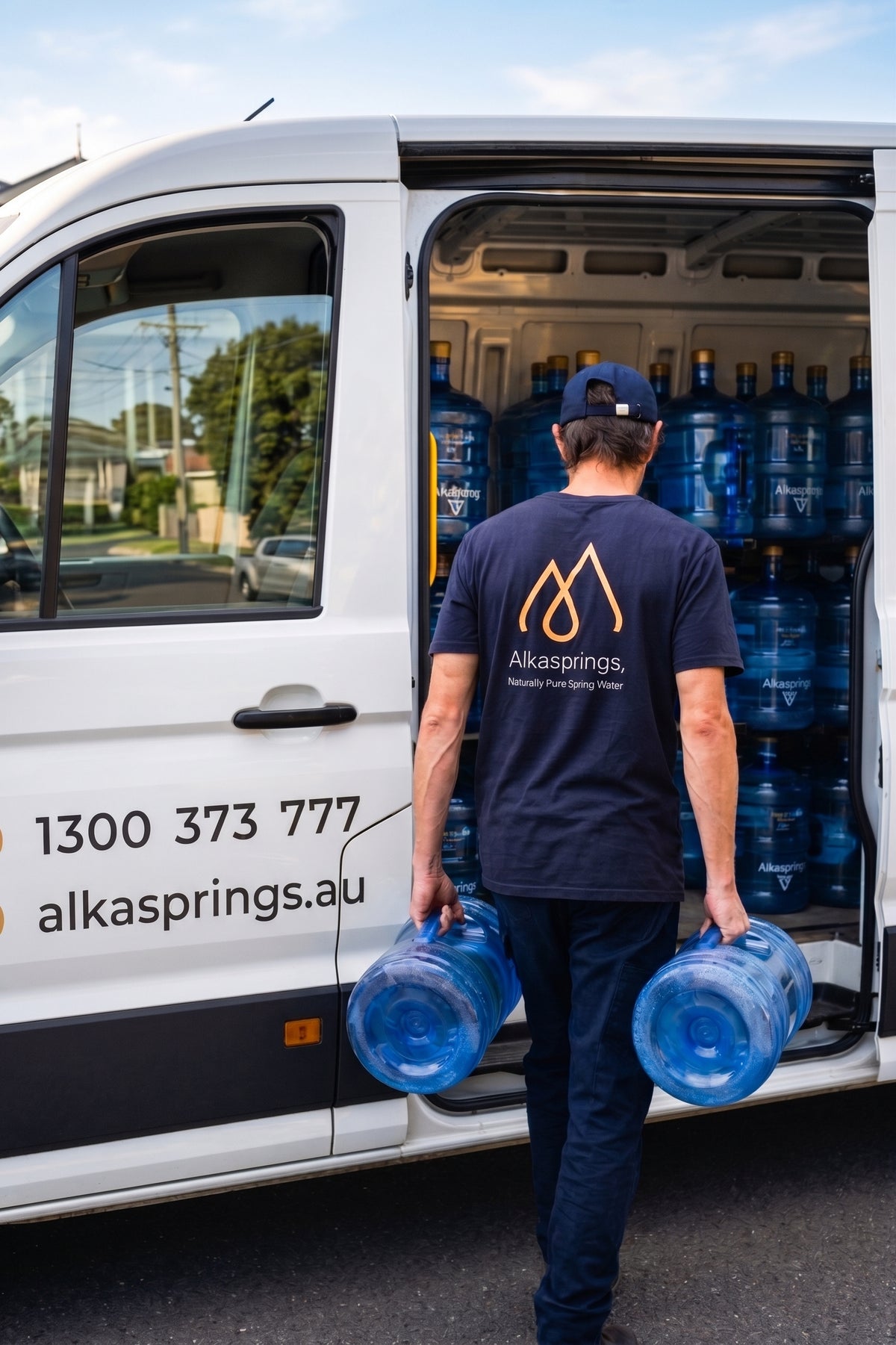 Alkasprings delivery driver carrying reusable bottles from a delivery van