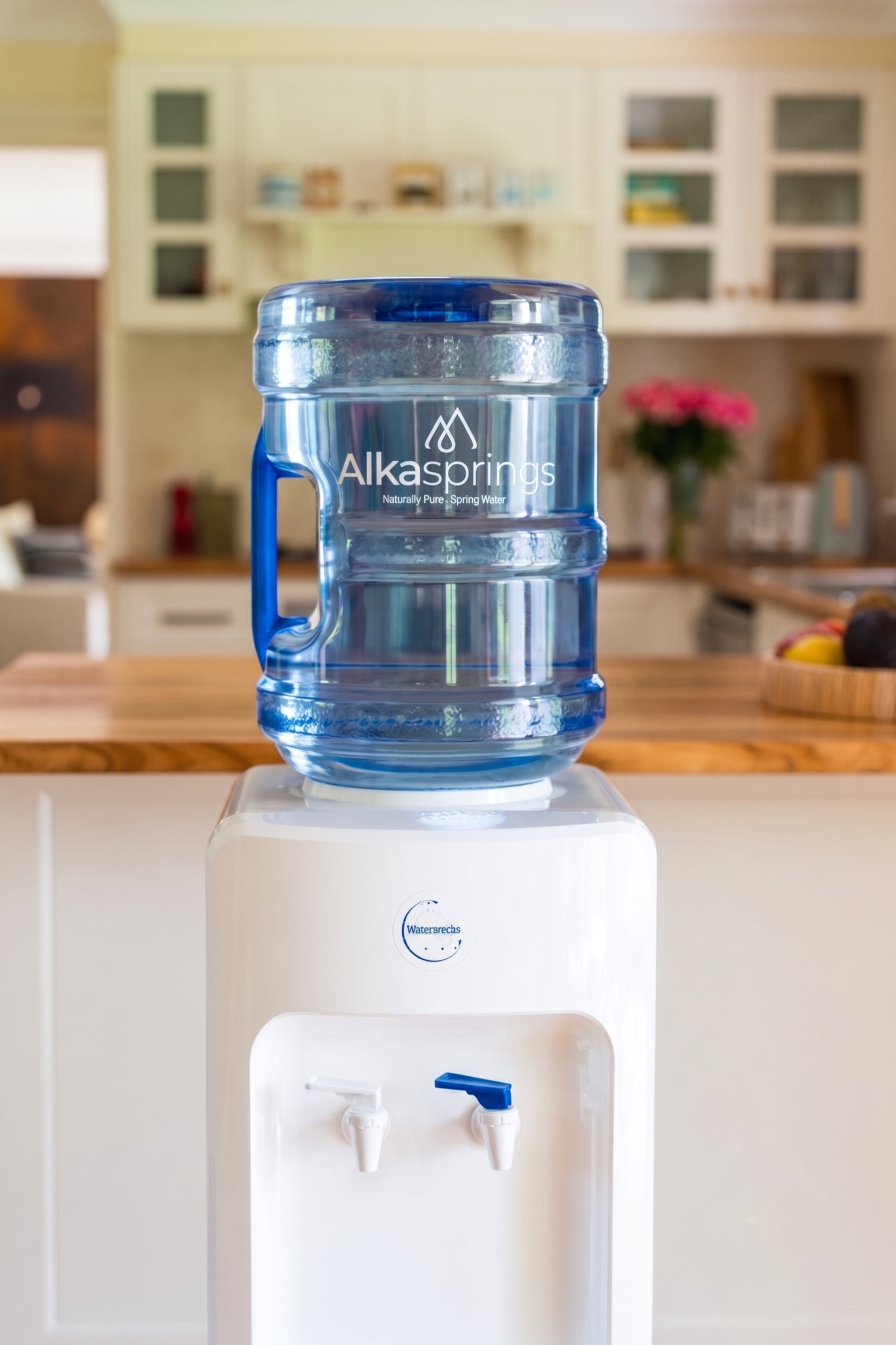 Alkasprings spring water bottle on a white water cooler in a home