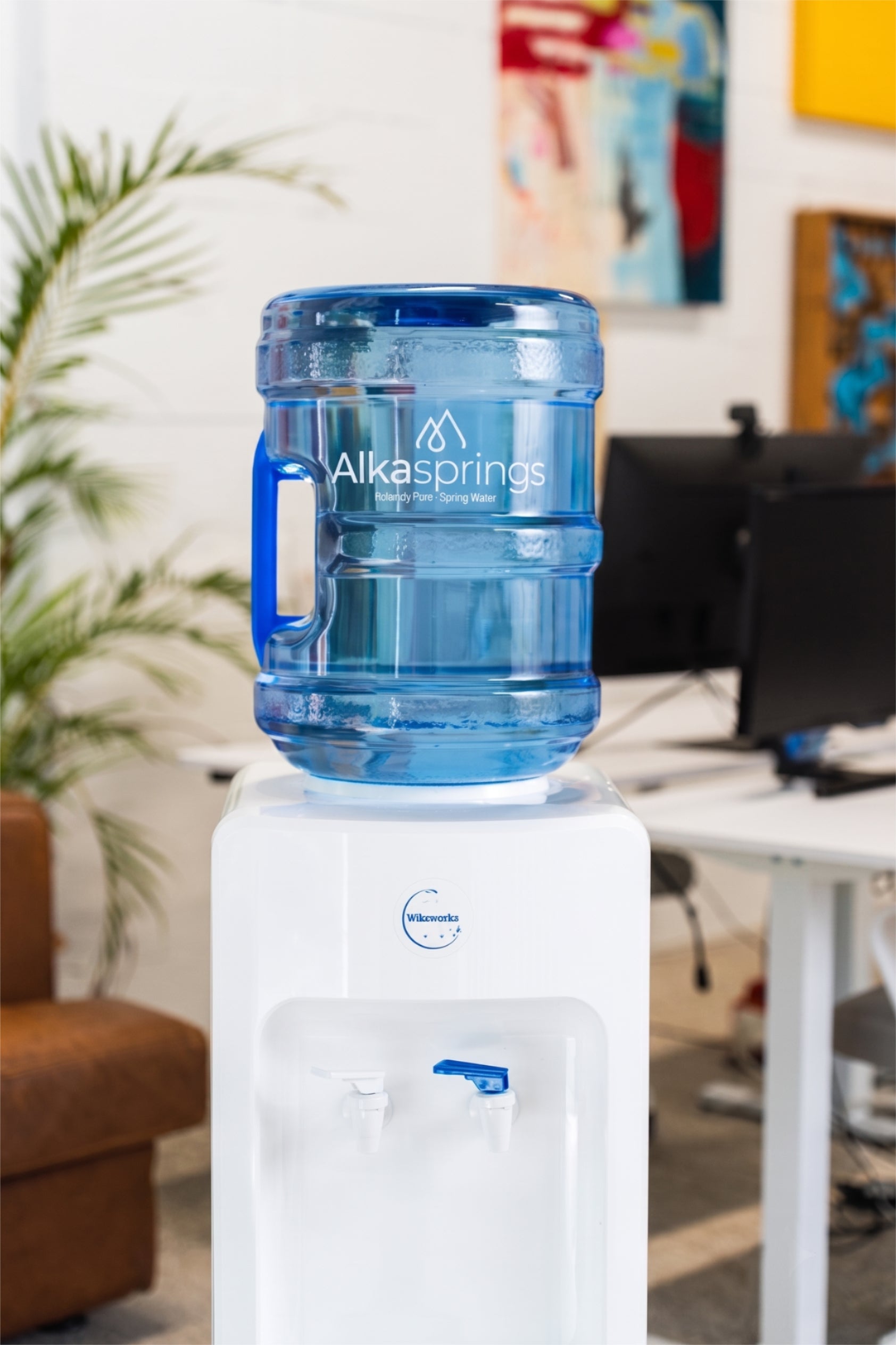 Alkasprings spring water bottle on a white water cooler in an office