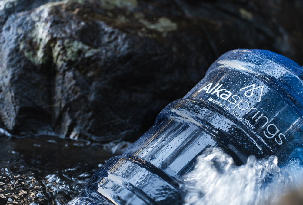 Close-up of an Alkasprings water bottle in flowing water