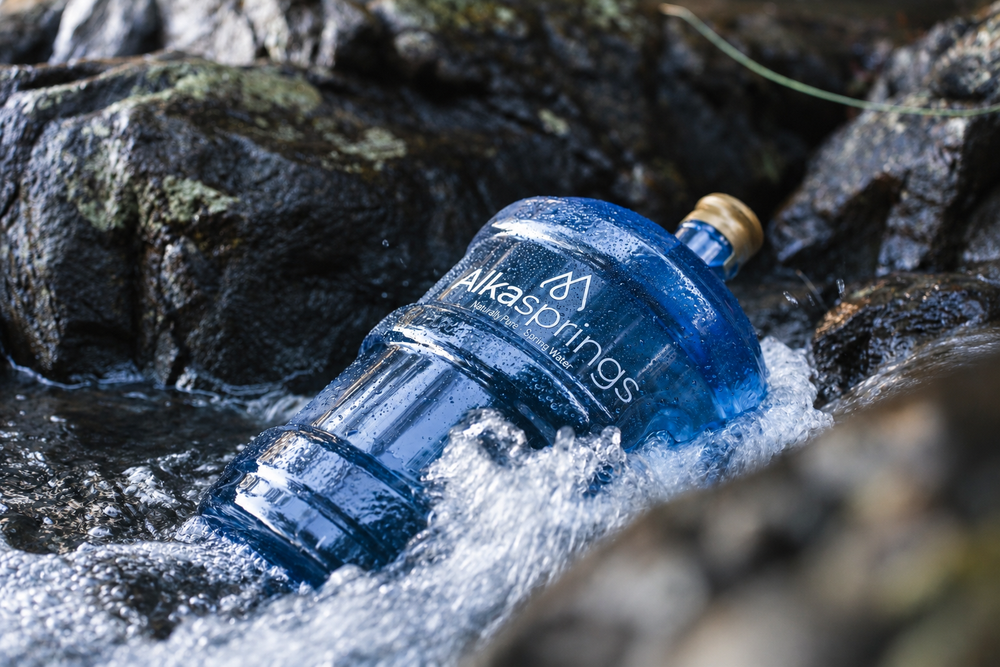 Alkasprings spring water bottle lying among rocks in a flowing stream